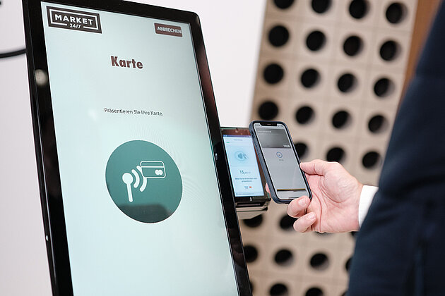 Digitale Transformation & Innovation Ein Monitor, daneben eine Zahlfunktion und eine Hand die mit dem Handy bezahlt.